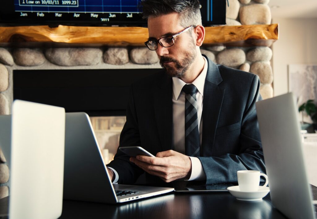 man holding phone laptop